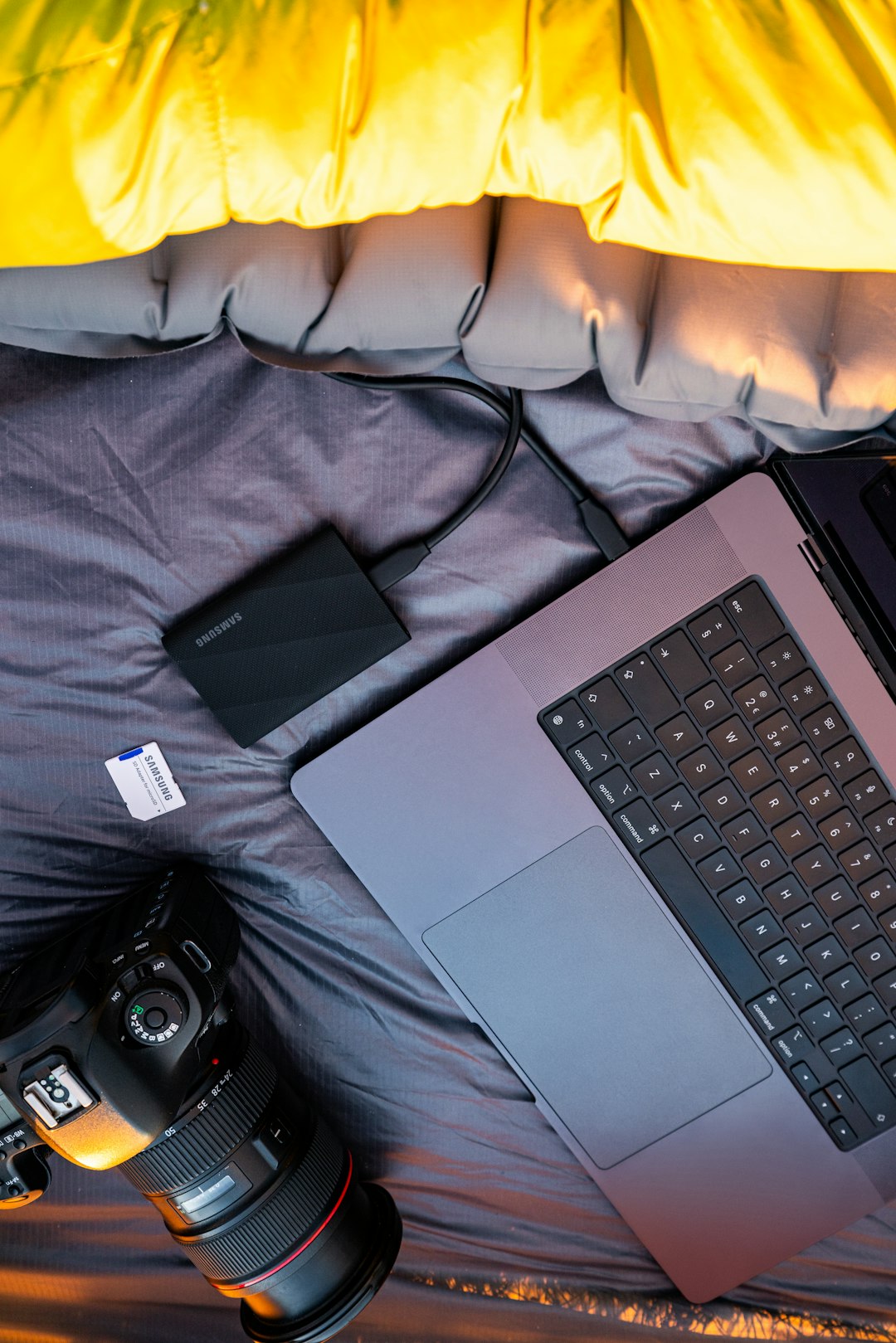 Laptop, camera, and external drive on sleeping bag